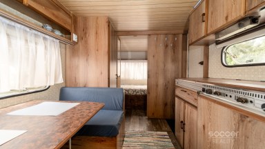 Příjemná venkovská zahrada s rekreačním karavanem a terasou.